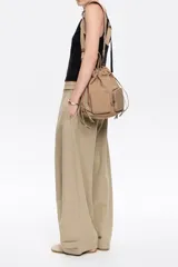 Mochila shopper de nylon color beige, con doble asa de mano, tiras ajustables y dos bolsillos frontales con cierre.