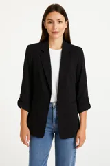 Blazer negro entallado con solapas de muesca, cierre frontal con un botón y mangas 3/4 con trabillas.