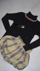 Polera negra de cuello alto con terminación rulotte en cuello, puños y cintura. Ideal para usar como base en looks de invierno.