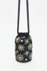 Cartera tipo tote bag de terciopelo negro con bordados de flores y estrellas de lentejuelas y mostacillas de colores. Tiene doble asa de cordón trenzado negro con cuentas en los extremos.