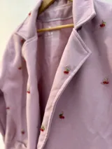 Blazer rosa con dijes de cerezas cosidos en el frente y en las mangas, corte oversize.