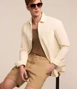 Camisa de hombre de corte regular, color borgoña, confeccionada en tela Oxford con efecto jaspeado. Tiene cuello inglés, abotonadura frontal, mangas largas con puños abotonados y bolsillo de parche en el pecho.