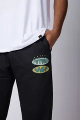 Pantalón de jogging negro de corte oversize, con puños elásticos y estampado con la palabra 'FUTURO' en verde y amarillo.
