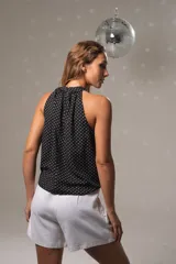 Musculosa negra con lunares blancos, cuello halter y botón en la parte trasera del cuello.