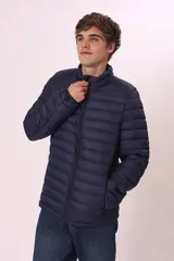 Campera puffer color verde militar, con cuello alto y cierre frontal. Diseño acolchado horizontal.