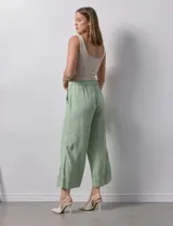 Pantalón de lino color crudo, de corte ancho y tiro alto, con bolsillos laterales y cintura elástica.