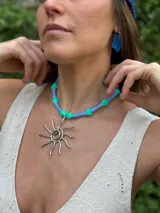 Collar con cuentas de acrílico color celeste y verde agua, con dije de sol plateado.
