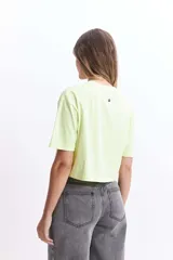 Remera corta color verde lima con estampado frontal de un corazón y la frase "love is a verb".