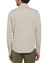 Camisa de hombre de manga larga con rayas horizontales en tonos beige y gris. Tiene cuello abotonado, bolsillo en el pecho y cierre con botones.
