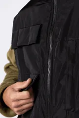 Campera negra con la parte superior de tela tipo rompevientos con dos bolsillos con solapa y la parte inferior de micro polar. Tiene cierre frontal y cuello alto.