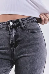 Pantalón de jean gris lavado, de tiro medio, corte ajustado en la cadera y acampanado desde la rodilla, con ruedo desflecado.