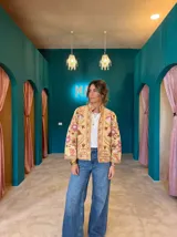 Chaqueta color crema con bordados florales en tonos rosados y terracota, de corte recto y cuello mao.