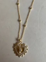 Collar dorado con cadena de eslabones y dije de corazón con borde de pequeñas piedras brillantes.