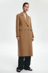 Abrigo largo color camel de Zara Woman Collection, confeccionado en hilatura con lana. Tiene cuello solapa con muescas, manga larga, falsos bolsillos delanteros, forro interior a contraste y cierre frontal con botones.