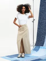 Falda larga de jean color beige claro, de corte recto con abertura frontal.