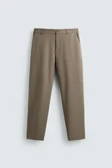 Pantalón regular fit color marrón, confeccionado en tejido elástico bidireccional. Cuenta con bolsillos frontales y bolsillos traseros de vivo con botón. Cierre frontal con cremallera y botón.