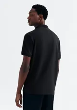 Camisa polo de piqué negro con cuello clásico y tapeta de dos botones.