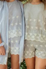 Conjunto de pijama gris a rayas verticales con bordados florales blancos, compuesto por musculosa de escote redondo y shorts con elástico en la cintura.