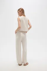 Pantalón de viscosa color beige, de corte ancho y tiro alto, con bolsillos laterales.
