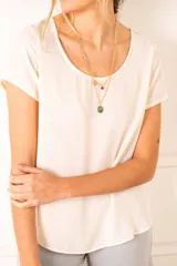 Blusa color crudo de poliéster con mangas cortas y cuello redondo.