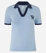 Blusa polo celeste de algodón con cuello y mangas cortas con ribete azul marino. Bordado "Seattle 78" en azul marino en el pecho.