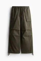 Pantalón cargo verde oliva de corte holgado, con cintura elástica ajustable con cordón, bolsillos laterales, bolsillos cargo con solapa y botón a presión en las piernas, bolsillos traseros con solapa y botón a presión, pliegues cosidos en las rodillas y cordón ajustable oculto en el bajo.