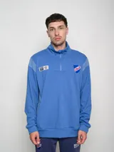 Buzo azul con medio cierre, de felpa con cortes, con el escudo del Club Nacional de Football bordado en el pecho y el logo de Umbro en la manga.