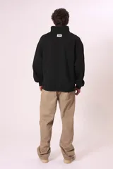 Sudadera negra con cierre de cremallera metálica en el cuello y estampado con texto en el pecho.