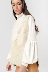 Chaleco de corderito en tonos beige, con diseño patchwork y un bolsillo lateral.