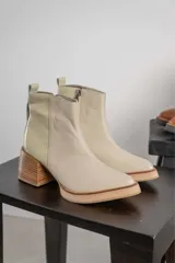 Bota corta de cuero marrón con puntera redondeada y taco cuadrado. Presenta una correa con hebilla alrededor del tobillo y cierre lateral.