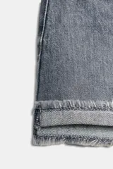 Shorts de jean de algodón, tiro alto, color azul claro desgastado. Presenta cinco bolsillos, cierre frontal con botón metálico y bajo desflecado con vuelta.