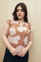 Blusa color marrón con estampado floral en tonos blanco y rosa, de corte holgado y mangas cortas.