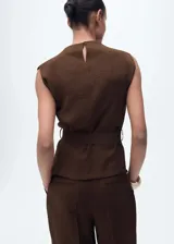 Blusa marrón sin mangas con cuello drapeado, trabillas, dos bolsillos de solapa en el pecho, cinturón desmontable y cierre de botón en la parte posterior.
