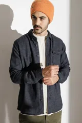 Camisa marrón de manga larga con cuello clásico, cierre con botones y bolsillo en el pecho.