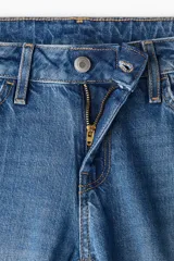 Jean de denim azul con corte slim regular, tiro medio, cinco bolsillos y cierre con cremallera y botón.