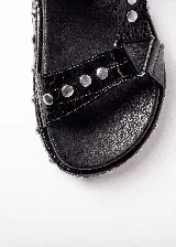 Sandalias marrones con textura de piel de cocodrilo, plataforma plana con tachas plateadas y tiras anchas con hebilla ajustable.