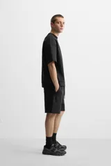 Sudadera negra de corte relaxed fit, confeccionada en tejido interlock de algodón con elasticidad. Tiene cuello redondo, manga corta y bajo acabado en rib.