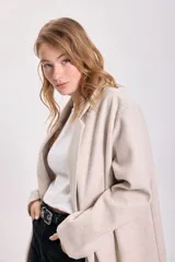 Tapado beige de corte recto con cuello solapa y cierre con un botón.
