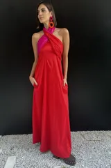 Vestido largo strapless con corpiño fruncido en color fucsia brillante y falda amplia en color rojo vibrante. La prenda tiene bolsillos laterales.