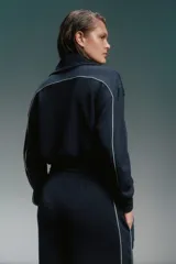 Conjunto deportivo azul marino con detalles de ribete blanco. Incluye una campera corta con cierre y un pantalón de corte recto.