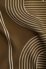 Pantalón de corte recto color marrón con estampado geométrico en blanco. Modelo de tiro alto con elástico en la parte posterior de la pretina y cierre oculto en un lateral.