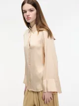 Camisa color durazno de corte amplio y fluido, con botones frontales y mangas largas.