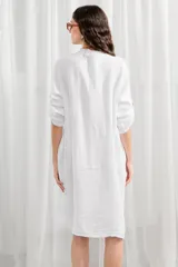Túnica blanca de lino, corte holgado, con cuello mao, cierre frontal con botones y mangas largas con trabillas para enrollar.