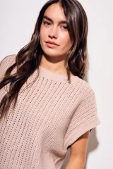 Chaleco de punto color beige con lurex, de corte recto y mangas cortas. Tejido calado con pequeños agujeros.