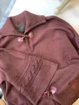 Saco capa tejido en lana color bordo, con cuello alto y cierre con broches tipo duffle-coat.