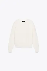 Sweater color blanco de punto perlado, con cuello redondo y mangas largas.