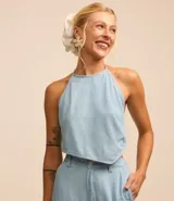 Top celeste de jeans con frente única, lazo en la espalda y detalle de caracolas en las puntas.