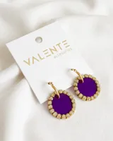 Aros colgantes con aro de acero dorado y dije circular de acrílico color violeta con borde de strass dorados.