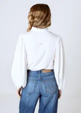 Camisa blanca de mangas largas abullonadas, con cuello mao y cierre frontal con botones.