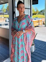 Kaftan largo con estampado floral en tonos turquesa y fucsia, con detalles de guarda pampa en los bordes.